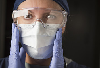 Image showing Female Doctor or Nurse Putting on Protective Facial Wear