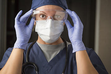 Image showing Female Doctor or Nurse Putting on Protective Facial Wear