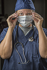 Image showing Female Doctor or Nurse Putting on Protective Facial Wear