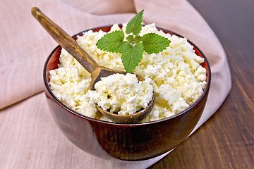 Image showing Curd in wooden bowl with spoon and mint on board