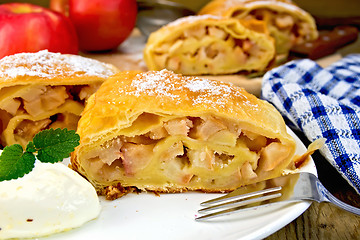 Image showing Strudel with apples in bowl with ice cream on board