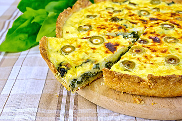 Image showing Pie with spinach and olives on fabric