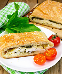 Image showing Roll filled with spinach and cheese on board with tomatoes