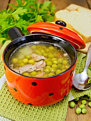 Image showing Soup from green peas with meat in red bowl and bread on board