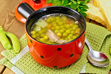 Image showing Soup from green peas with meat in red bowl on napkin