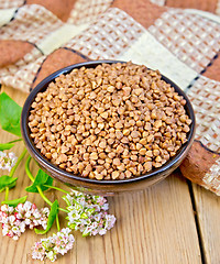 Image showing Buckwheat in brown bowl with flower on board