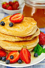 Image showing Flapjacks with strawberries and blueberries on linen tablecloth