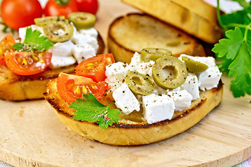 Image showing Sandwich with feta and olives on wooden board