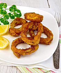 Image showing Calamari fried with lemon and fork on plate and napkin