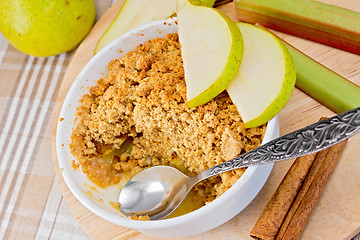 Image showing Crumble with pears and rhubarb in bowl on linen tablecloth