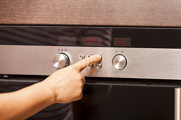 Image showing Close Up of Hand Turning Knob on Oven