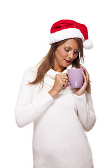 Image showing Cold young woman in a Santa hat sipping coffee tea