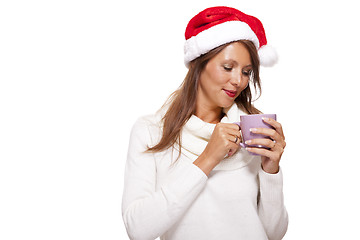 Image showing Cold young woman in a Santa hat sipping coffee tea