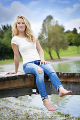 Image showing Blond woman sitting on a jetty