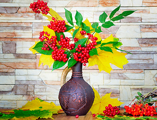 Image showing Autumn still life: berries and autumn leaves in a ceramic vase.