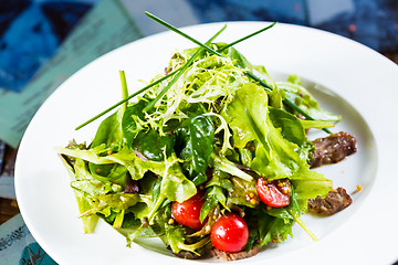 Image showing Fresh vegetable salad with meat and cherry tomatoes on white plate.