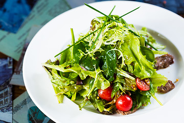 Image showing Fresh vegetable salad with meat and cherry tomatoes on white plate.