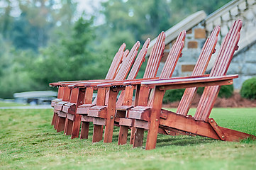 Image showing Two wooden adirondack chairs on lush green lawn