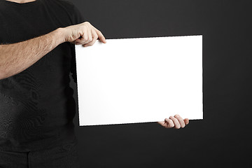 Image showing Man in black clothes holds poster