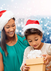 Image showing happy mother and girl in santa hats with gift box