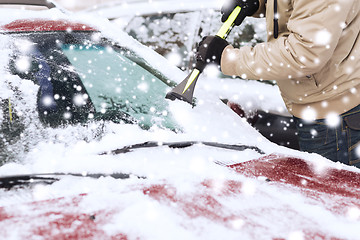 Image showing closeup of man cleaning snow from car