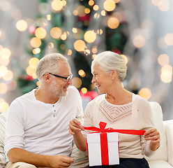 Image showing happy senior couple with gift box at home