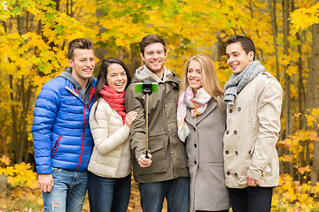 Image showing smiling friends with smartphone in city park