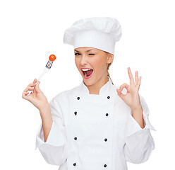 Image showing smiling female chef with fork and tomato