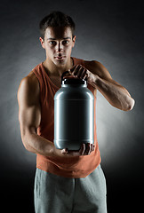 Image showing young male bodybuilder holding jar with protein