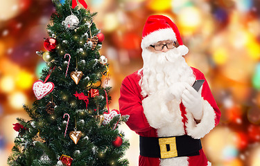 Image showing santa claus with smartphone and christmas tree