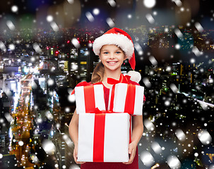 Image showing smiling little girl in santa helper hat with gifts