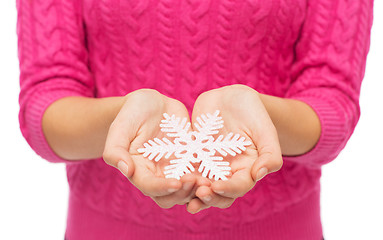 Image showing close up of woman in sweater holding snowflake