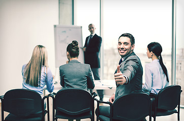 Image showing businessman with team showing thumbs up in office