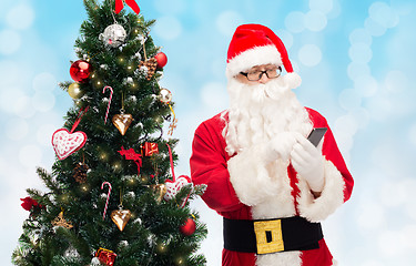 Image showing santa claus with smartphone and christmas tree