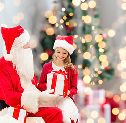 Image showing smiling little girl with santa claus and gifts