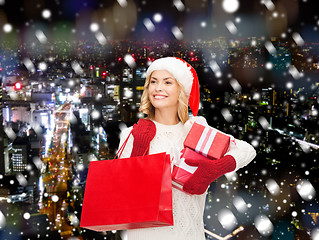 Image showing smiling young woman in santa helper hat with gifts