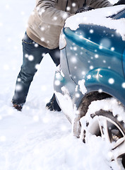 Image showing closeup of man pushing car stuck in snow