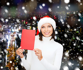 Image showing smiling woman in santa hat with greeting card