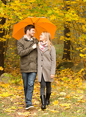 Image showing smiling couple with umbrella in autumn park