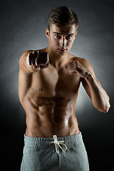 Image showing young man on fighting stand over black background