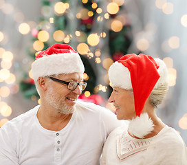 Image showing happy senior couple in santa helper hats