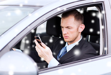 Image showing close up of man using smartphone while driving car