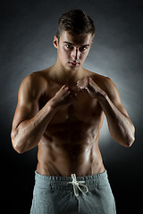 Image showing young man on fighting stand over black background