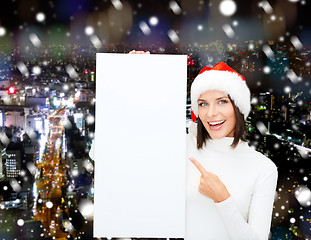 Image showing smiling young woman in santa hat with white board