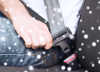 Image showing close up of man fastening seat belt in car