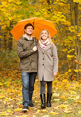 Image showing smiling couple with umbrella in autumn park