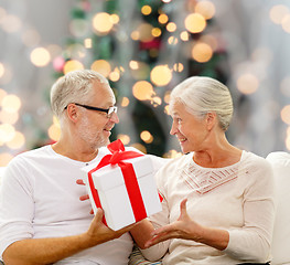 Image showing happy senior couple with gift box at home