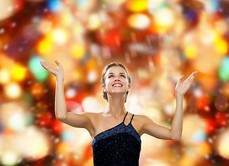 Image showing smiling woman raising hands and looking up