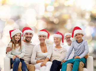 Image showing happy family in santa helper hats sitting on couch