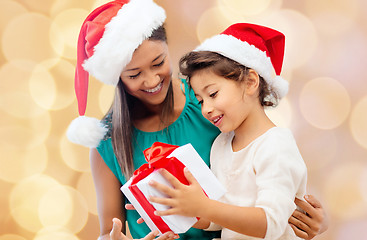 Image showing happy mother and girl in santa hats with gift box